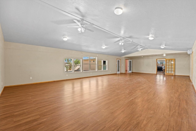 unfurnished living room featuring ceiling fan, vaulted ceiling, a textured ceiling, and light wood-type flooring