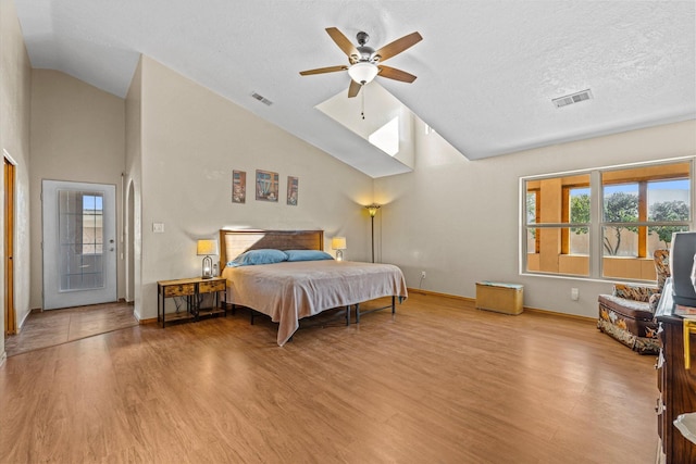 bedroom featuring access to exterior, light hardwood / wood-style floors, multiple windows, and a textured ceiling