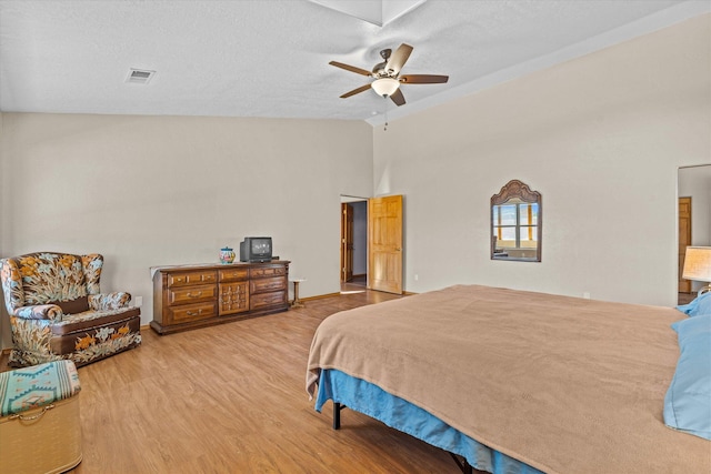 bedroom featuring ceiling fan, vaulted ceiling, a textured ceiling, and light wood-type flooring