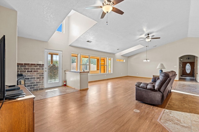 living room featuring lofted ceiling, ceiling fan with notable chandelier, a textured ceiling, and light hardwood / wood-style floors