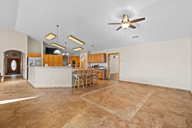 kitchen featuring appliances with stainless steel finishes, decorative light fixtures, lofted ceiling, a kitchen bar, and ceiling fan