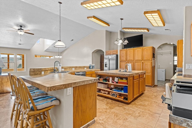 kitchen featuring pendant lighting, sink, a kitchen breakfast bar, a center island, and stainless steel refrigerator with ice dispenser