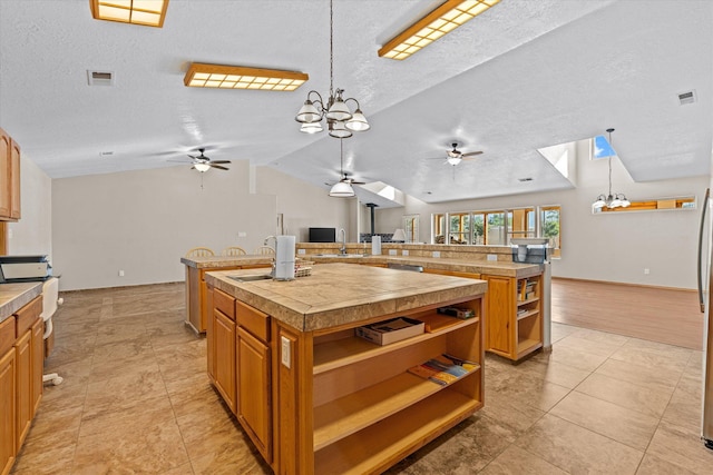 kitchen featuring a large island, vaulted ceiling, hanging light fixtures, and a textured ceiling