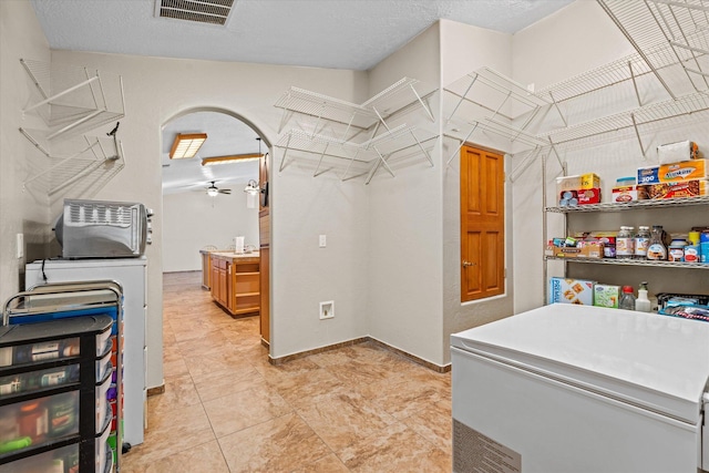 laundry room with separate washer and dryer, a textured ceiling, and ceiling fan