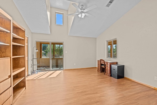 unfurnished office featuring ceiling fan, vaulted ceiling, a textured ceiling, and light wood-type flooring