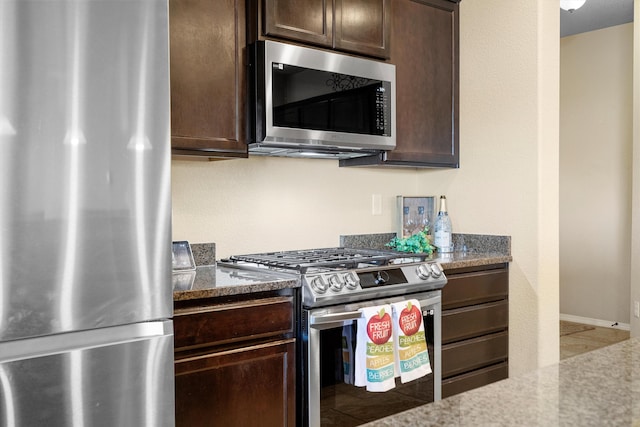 kitchen with dark brown cabinetry, stainless steel appliances, and stone counters