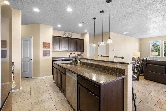 kitchen with pendant lighting, dishwasher, sink, dark brown cabinetry, and a center island with sink