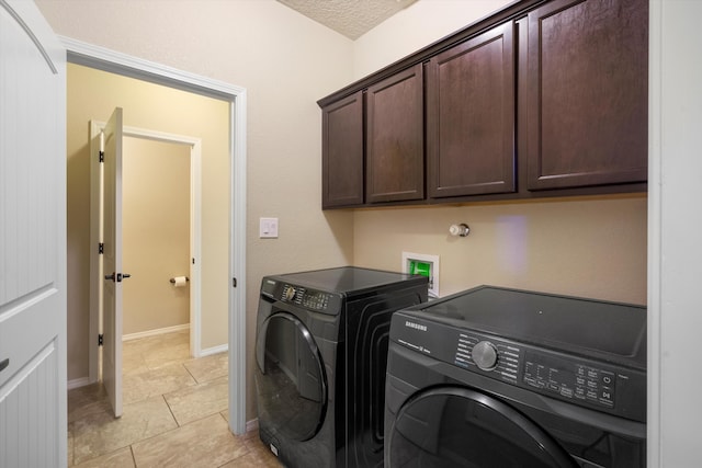 washroom with cabinets, washing machine and dryer, light tile patterned floors, and a textured ceiling