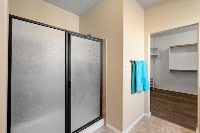 bathroom featuring walk in shower, tile patterned floors, and a textured ceiling