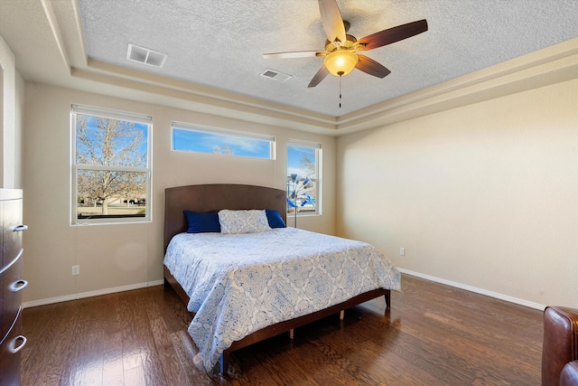 bedroom featuring multiple windows, dark hardwood / wood-style floors, and a textured ceiling