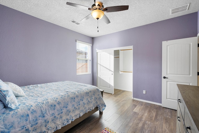 bedroom with wood-type flooring, ceiling fan, and a textured ceiling