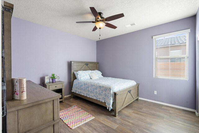 bedroom with wood-type flooring, ceiling fan, and a textured ceiling