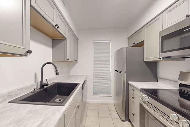 kitchen with stainless steel appliances, sink, gray cabinetry, and light tile patterned floors