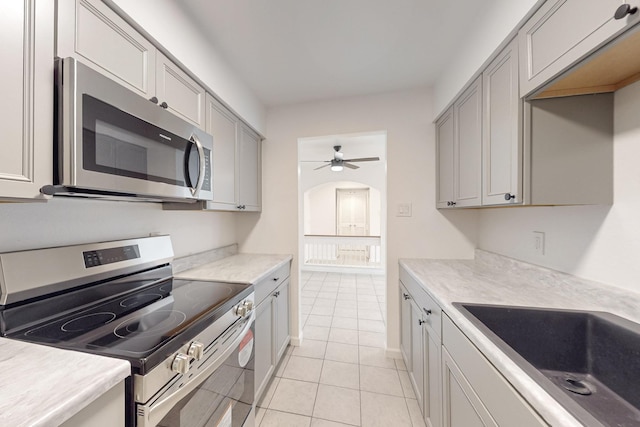 kitchen with sink, light tile patterned floors, gray cabinets, ceiling fan, and appliances with stainless steel finishes