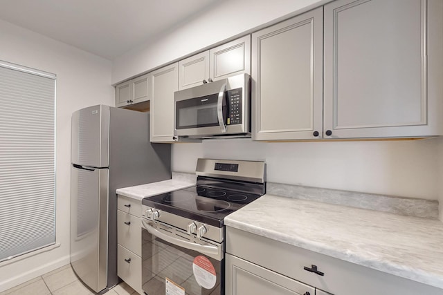 kitchen with gray cabinetry, stainless steel appliances, and light tile patterned flooring