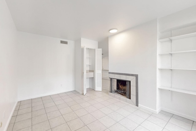 unfurnished living room featuring a tile fireplace and light tile patterned floors