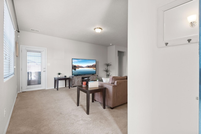 living area with light carpet, baseboards, visible vents, and a textured ceiling