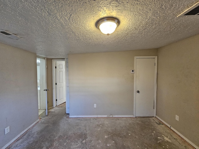 unfurnished room featuring a textured ceiling and concrete floors