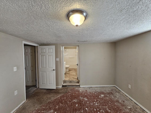 unfurnished bedroom with ensuite bathroom and a textured ceiling