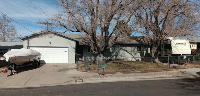 ranch-style home featuring concrete driveway, a garage, a fenced front yard, and stucco siding