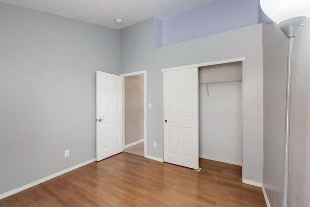 unfurnished bedroom featuring wood-type flooring, a textured ceiling, and a closet