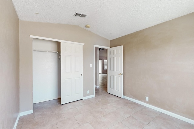 unfurnished bedroom with lofted ceiling, a textured ceiling, and a closet