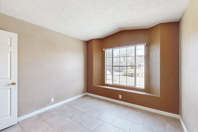 spare room with lofted ceiling, light tile patterned floors, and a textured ceiling