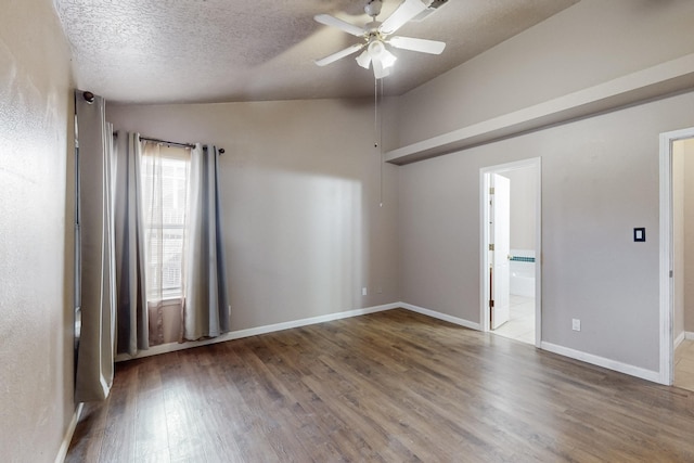 empty room featuring ceiling fan, dark hardwood / wood-style floors, vaulted ceiling, and a textured ceiling