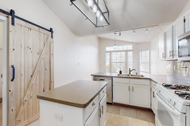 kitchen featuring appliances with stainless steel finishes, sink, white cabinets, a center island, and a barn door