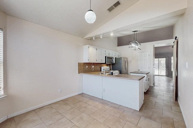 kitchen with white cabinetry, decorative light fixtures, kitchen peninsula, stainless steel appliances, and a barn door