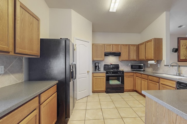 kitchen featuring tasteful backsplash, sink, light tile patterned floors, and black appliances