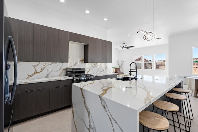 1145 15th St SE, Rio Rancho, NM 87124 - kitchen with pendant lighting, sink, stainless steel gas range, a center island with sink, and a kitchen bar