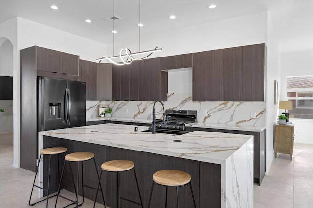 1145 15th St SE, Rio Rancho, NM 87124 - kitchen with light stone counters, hanging light fixtures, a breakfast bar area, and a center island with sink