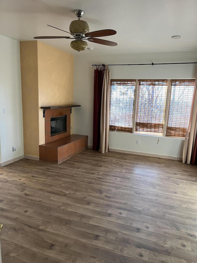 unfurnished living room with ceiling fan, a fireplace, and wood-type flooring