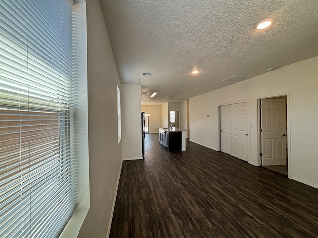 6232 Winter Hawk Dr NE, Rio Rancho, NM 87144 - unfurnished living room with visible vents, baseboards, a textured ceiling, and dark wood-style flooring