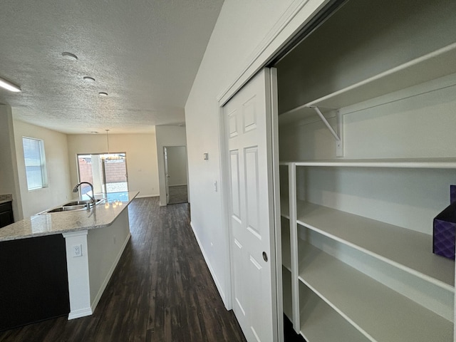 6232 Winter Hawk Dr NE, Rio Rancho, NM 87144 - kitchen featuring light stone countertops, dark wood finished floors, a kitchen island with sink, a sink, and a textured ceiling