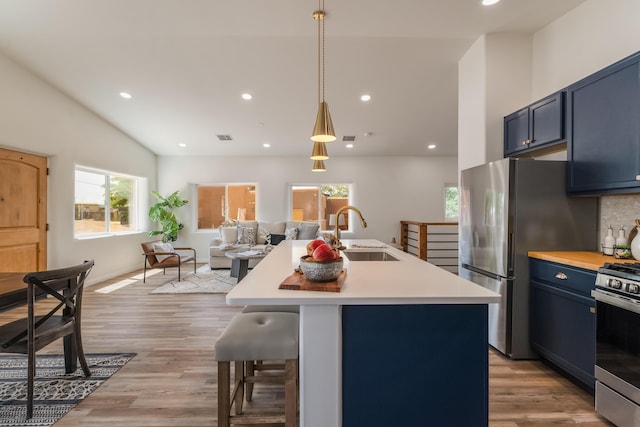 kitchen featuring blue cabinets, an island with sink, appliances with stainless steel finishes, and sink