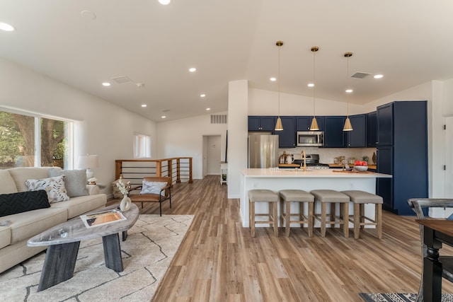 living room with lofted ceiling, sink, and light hardwood / wood-style flooring