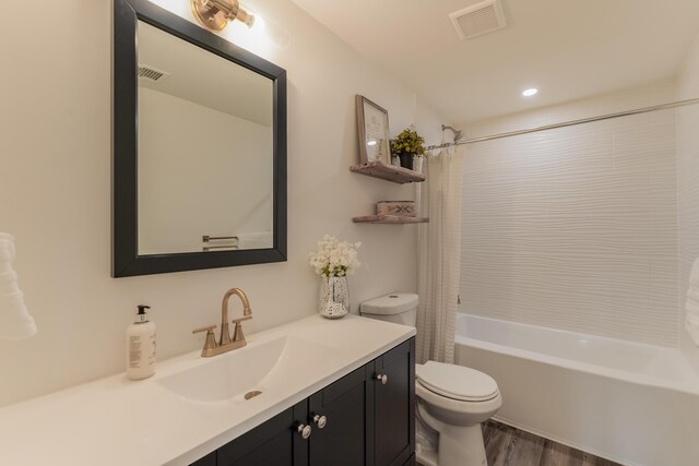 full bathroom featuring vanity, hardwood / wood-style floors, shower / bath combo, and toilet