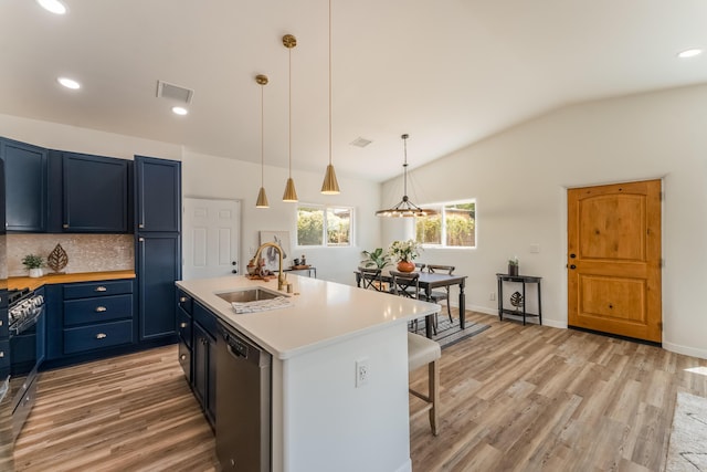 kitchen featuring blue cabinetry, sink, hanging light fixtures, stainless steel appliances, and a kitchen island with sink