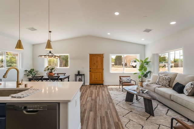 living room with sink, vaulted ceiling, light hardwood / wood-style floors, and a healthy amount of sunlight