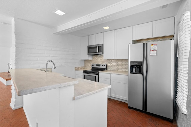 kitchen featuring a textured ceiling, appliances with stainless steel finishes, light stone countertops, decorative backsplash, and white cabinets