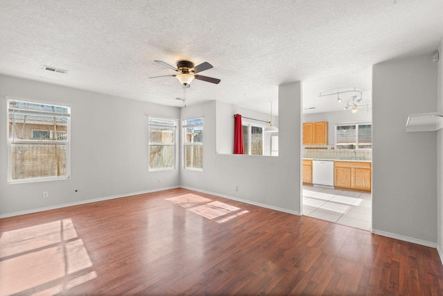 unfurnished living room with ceiling fan, sink, a textured ceiling, and light hardwood / wood-style floors