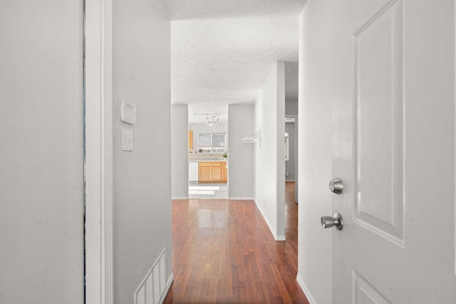 hall with hardwood / wood-style floors and a textured ceiling