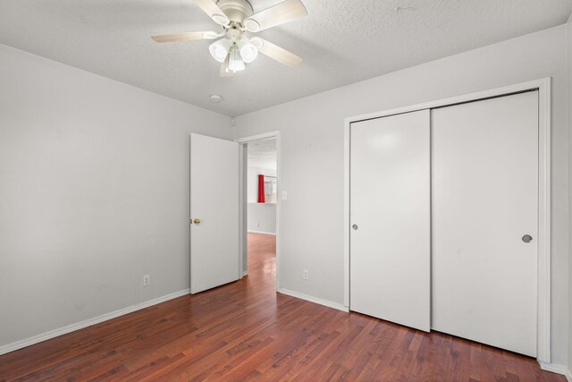 unfurnished bedroom with a textured ceiling, a closet, dark hardwood / wood-style floors, and ceiling fan