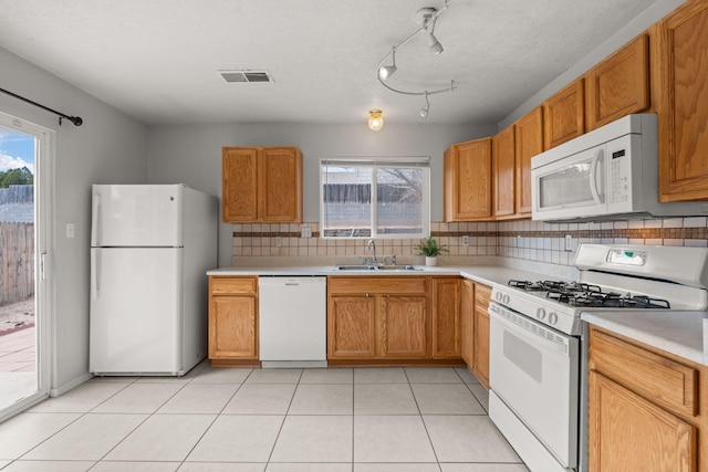 kitchen with sink, white appliances, tasteful backsplash, light tile patterned floors, and a textured ceiling