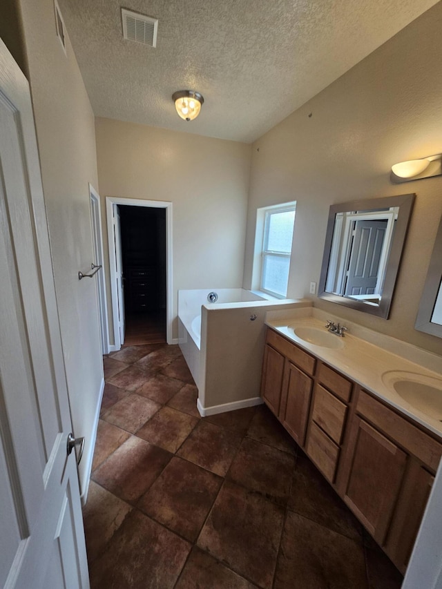 bathroom featuring vanity, a tub, and a textured ceiling