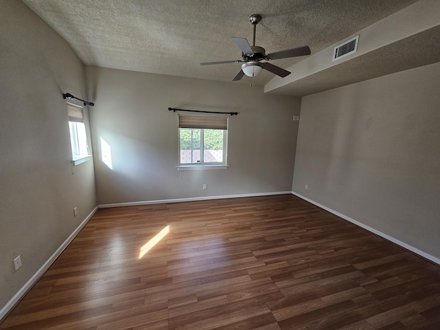 empty room with ceiling fan, dark wood-type flooring, and a textured ceiling