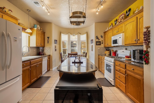 kitchen with pendant lighting, sink, white appliances, light tile patterned floors, and tasteful backsplash