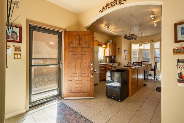 kitchen featuring sink, light tile patterned floors, stainless steel refrigerator, and a kitchen island